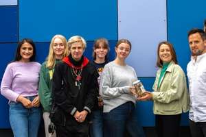 Foto: Eine Gruppe Schüler:innen übergibt ein Spendenglas an Hannah Dehning von Fluchtraum Bremen e.V.