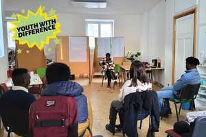 Foto: junge Leute sitzen im Seminarraum, eine junge Frau gibt den Workshop